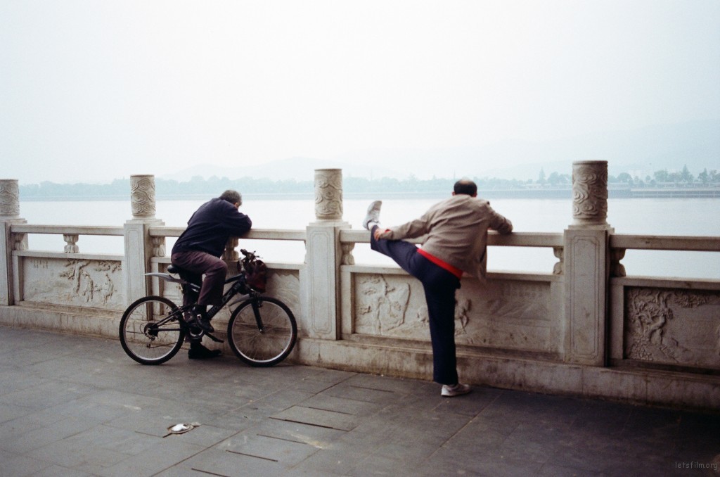 骑自行车的老人好奇压腿的老人在看什么，也停下车一起看。热闹的长沙人也总爱热闹。
